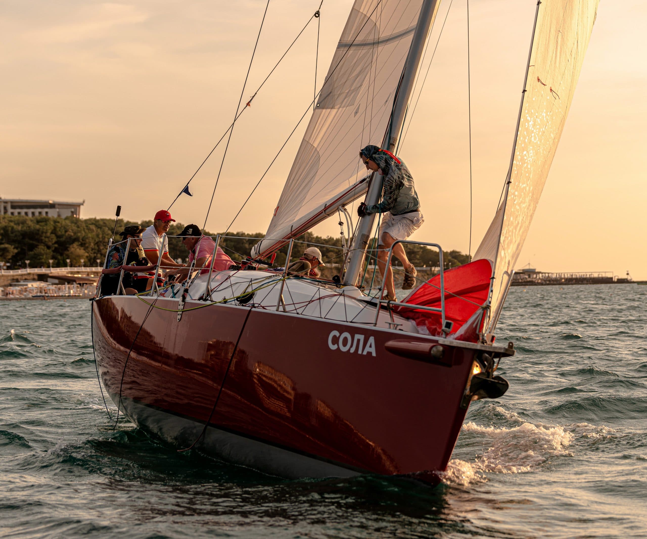 The red yacht Sola sailing at sunset.