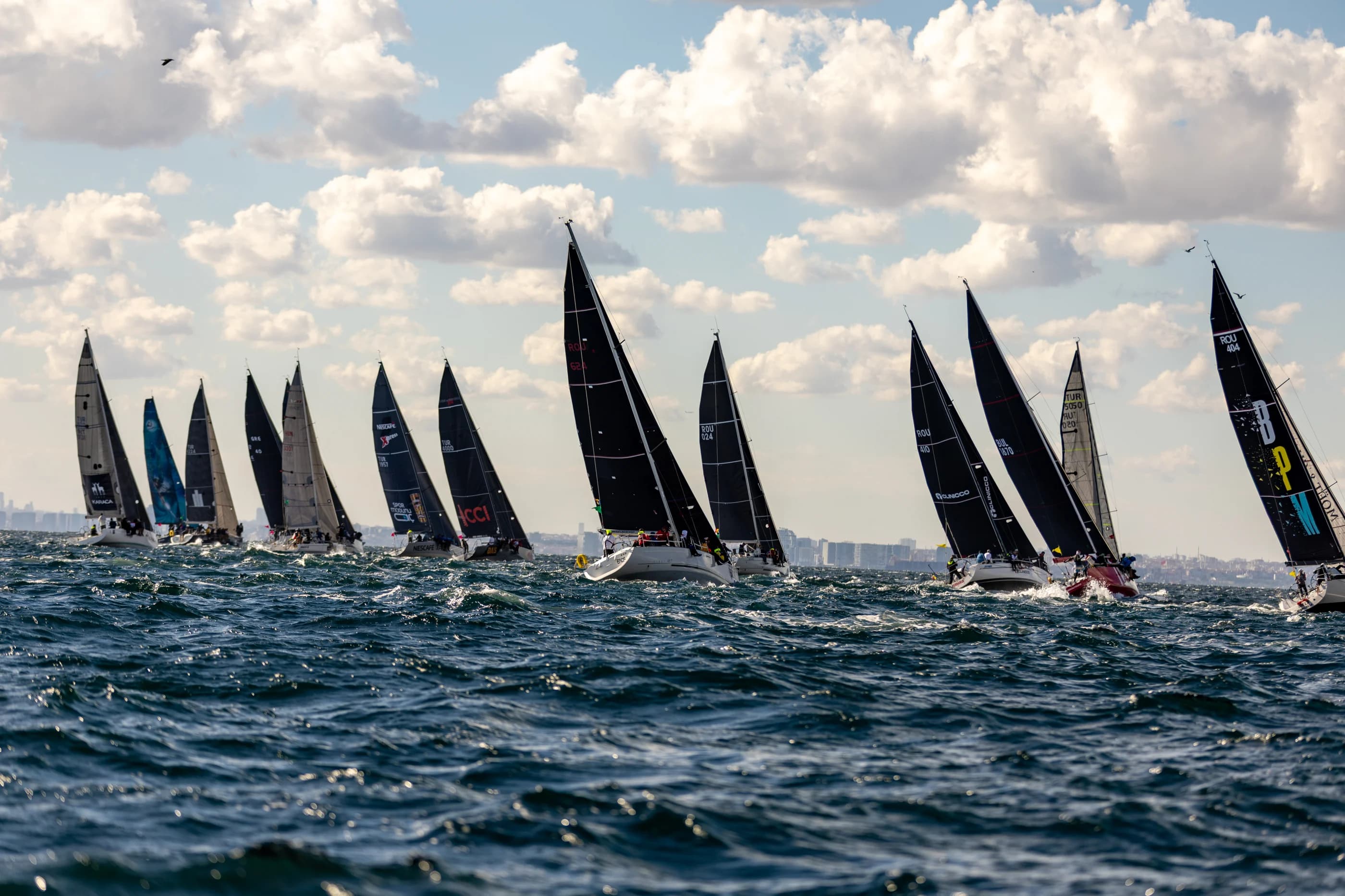 The Bosphorus Cup fleet powering through choppy water beneath a bright Istanbul sky.