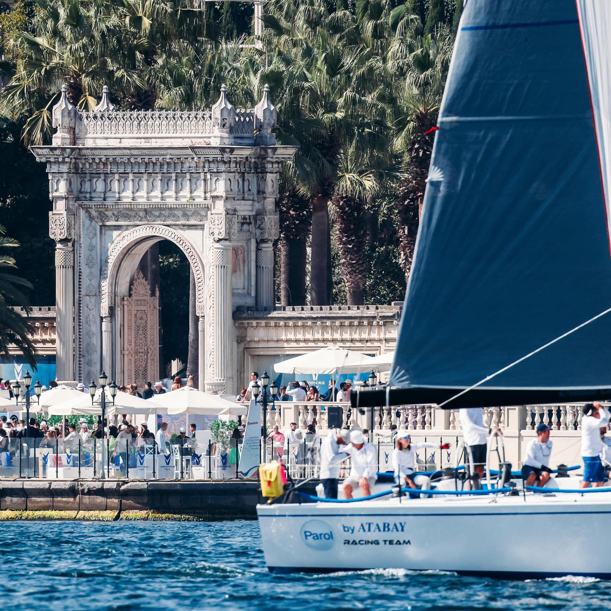 A racing yacht passes the Bosphorus Cup hospitality area at Çırağan Palace.